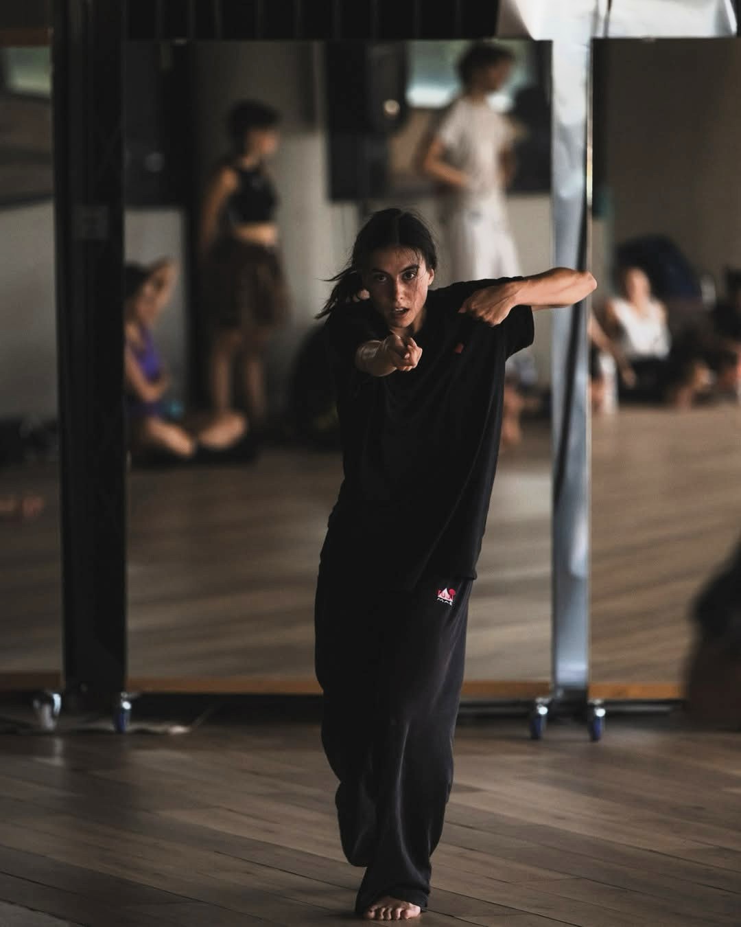 The picture shows teacher Montse dancing in the studio, looking at the camera and extending their arms