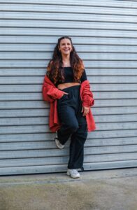 This picture shows teacher Missa outside in a red and black outfit, leaning against a wall outside